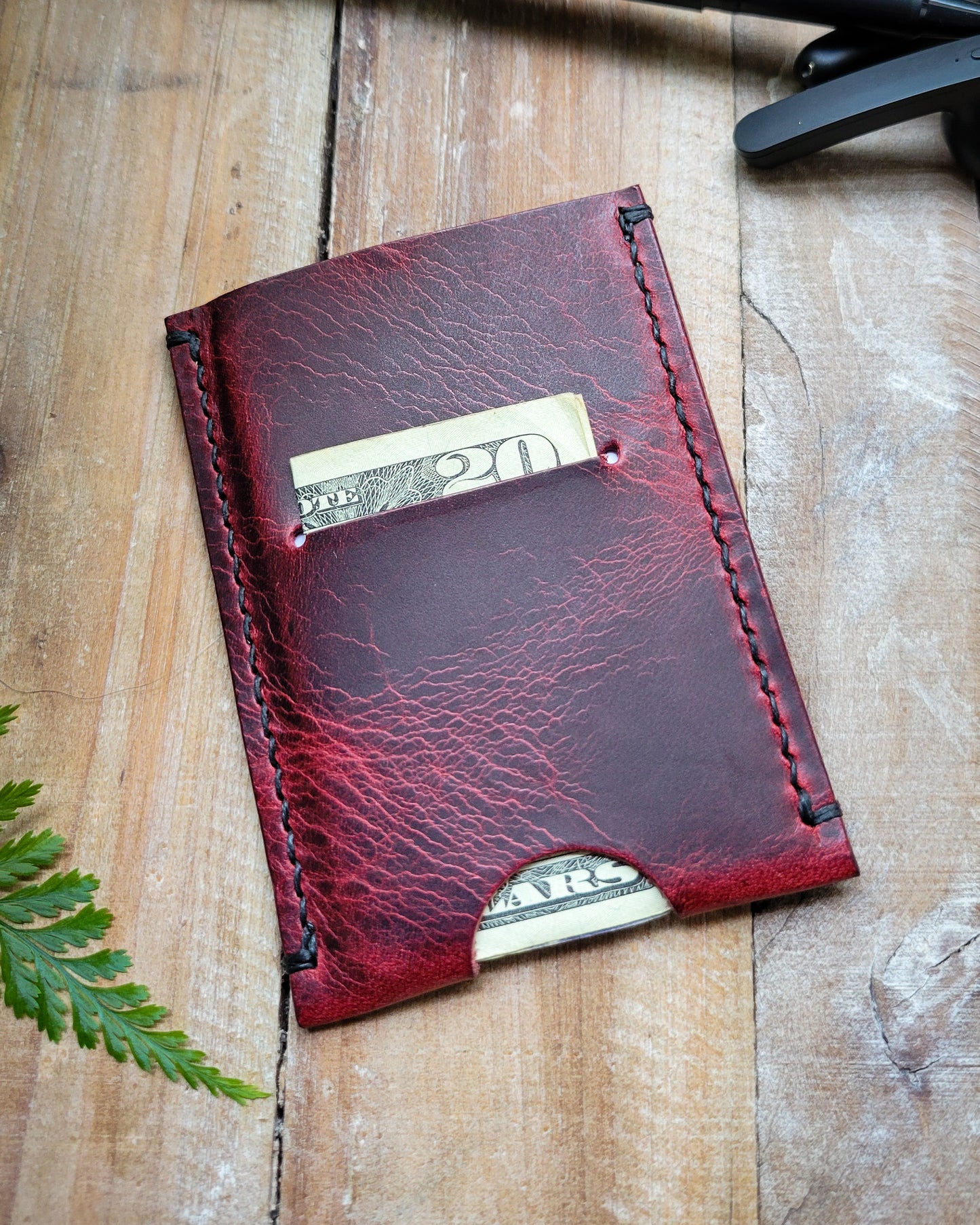 Red leather wallet with money sticking out on a wooden surface