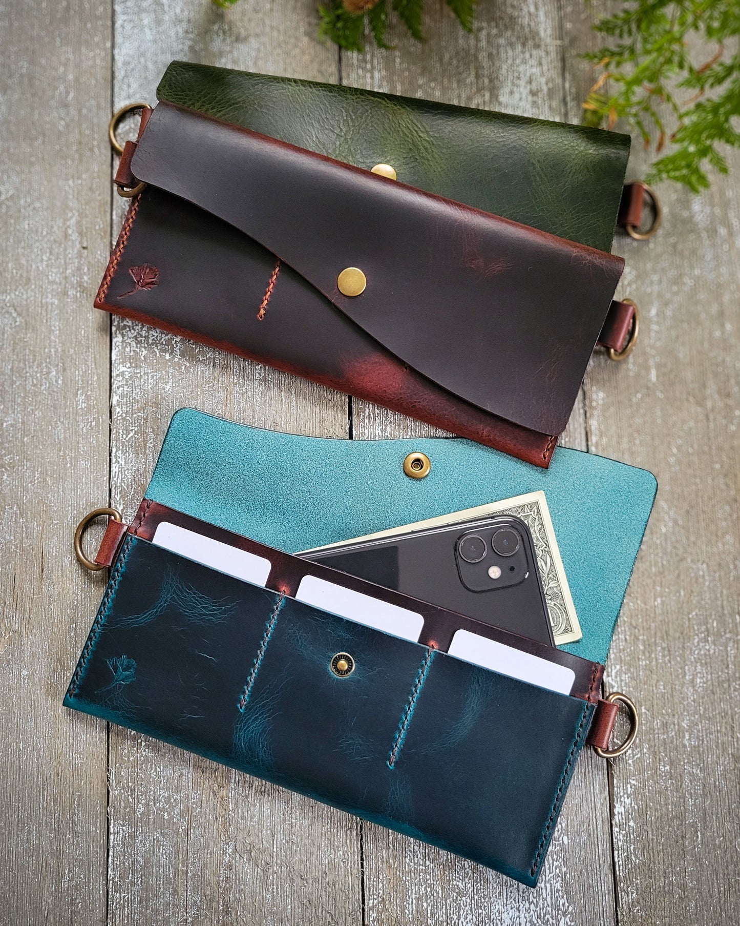 Three leather crossbody purses laid flat, displaying card pockets and a main compartment. One purse is green, one is brown, and one is blue.