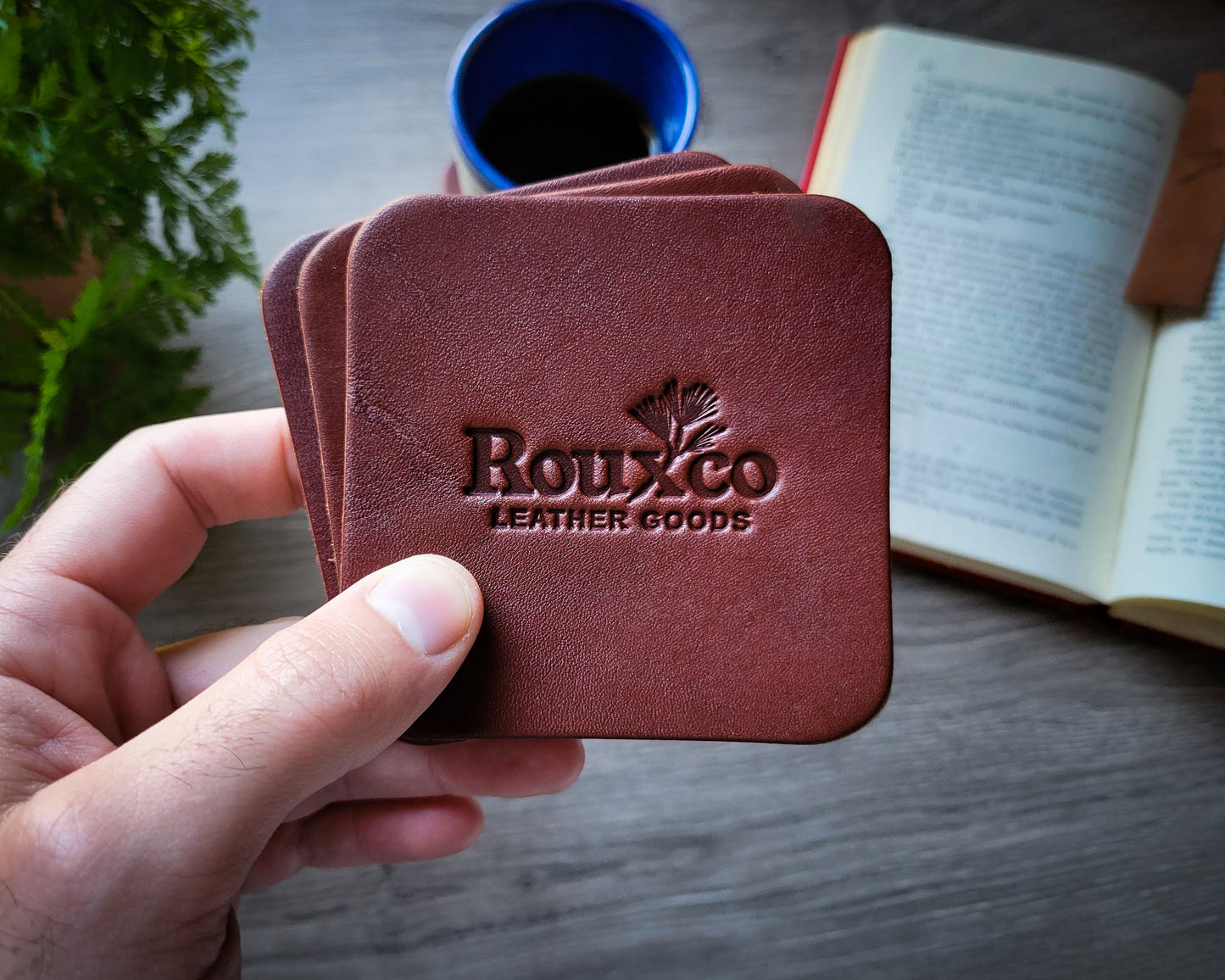 Brown Wickett & Craig leather coaster held in hand with open book in the background