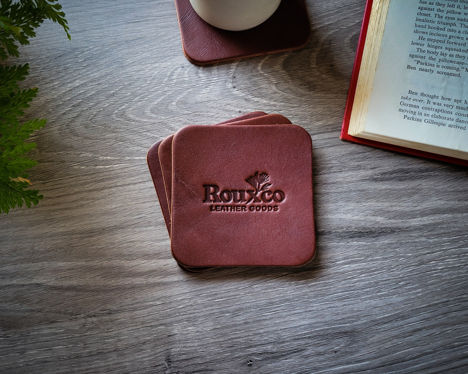 Brown Wickett & Craig leather coaster laying on desk with open book in the background