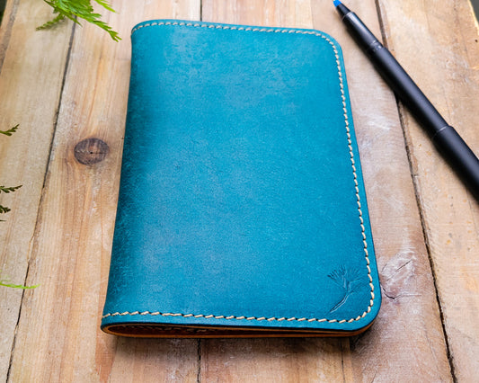 Blue Italian leather notebook cover laying closed on a rugged wooden background