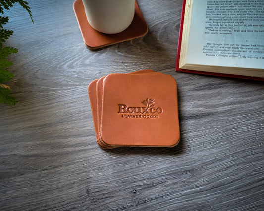 Tan Wickett & Craig leather coasters laying on desk with open book 