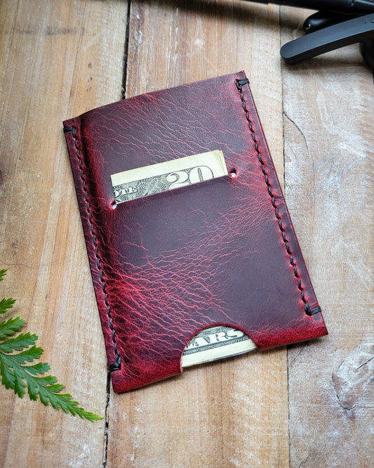 Red leather wallet with money sticking out on a wooden surface