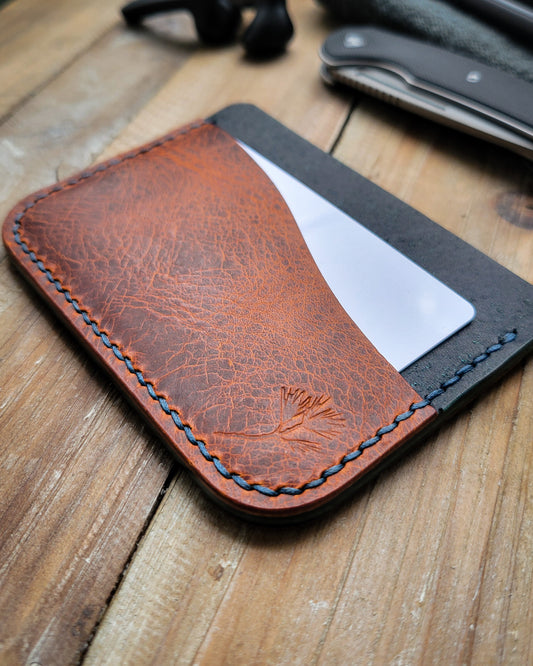 Brown leather wallet with navy blue stitching on a wooden surface
