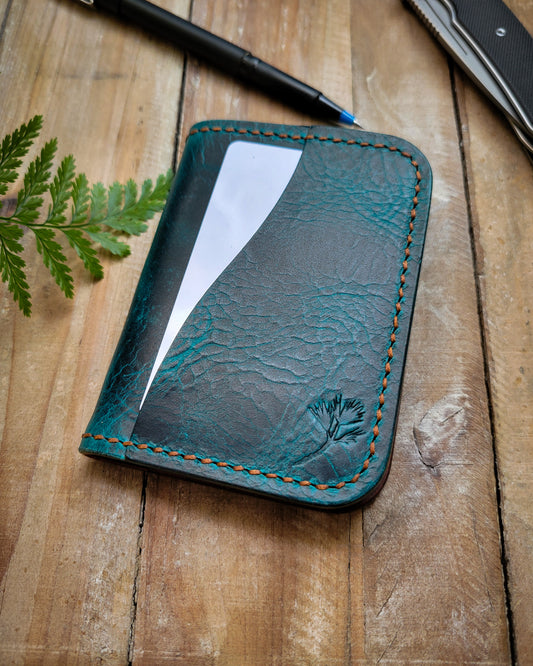 Blue leather wallet with stitching on a wooden surface