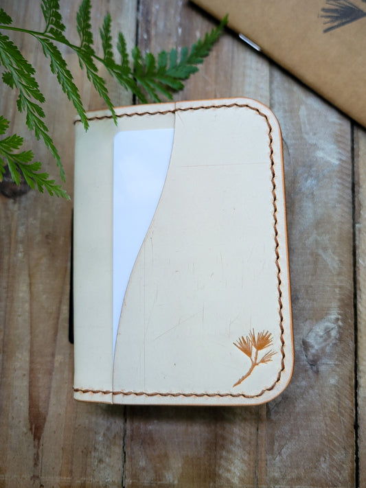 Handmade leather cardholder with floral design on a wooden surface