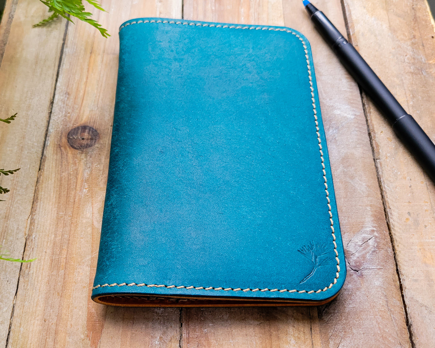 Blue Italian leather notebook cover laying closed on a rugged wooden background